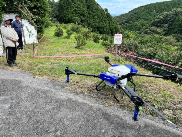 農薬散布ドローンのフライトを見学する農家の人たち